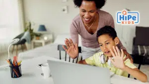 Jeune garçon et sa mère afro-américaines prenant des cours d'anglais en visio à la maison.