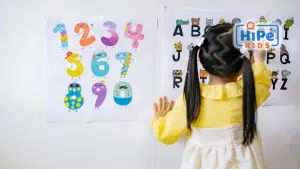 Petite fille de dos qui apprend l'alphabet et à compter.