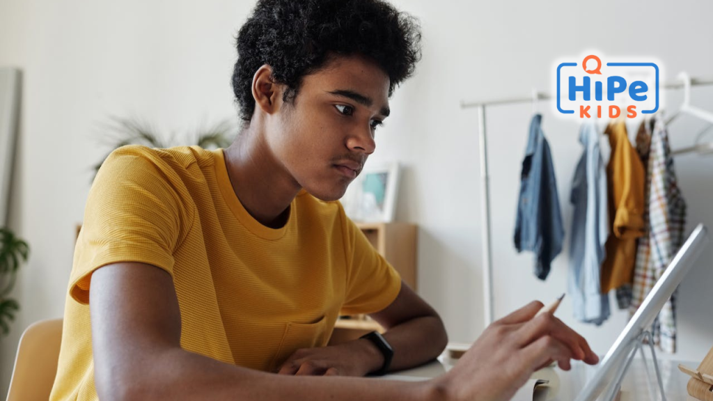 Adolescent noir assis à son bureau et préparant son bac international sur sa tablette.